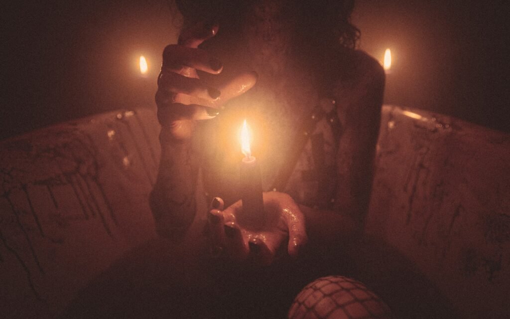 candle in center of hands with black paint on nails