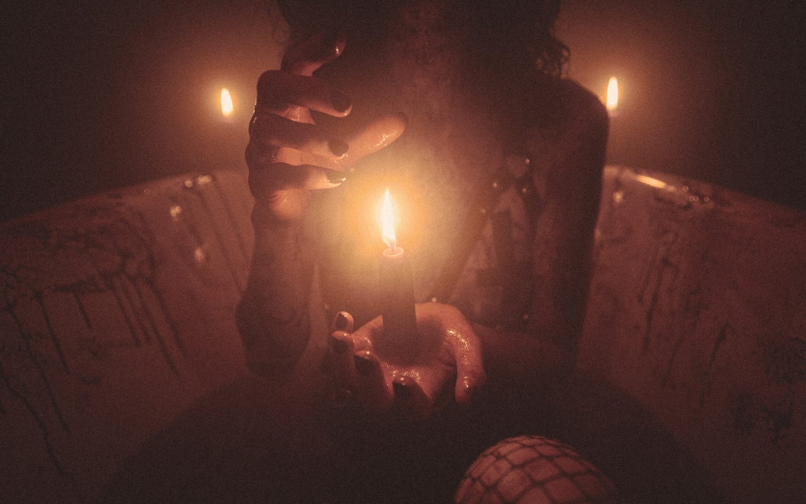 candle in center of hands with black paint on nails